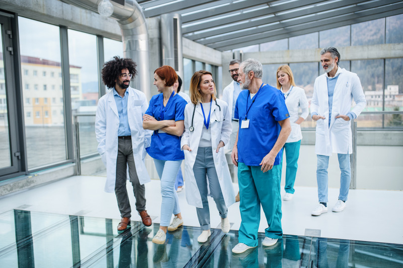 Front view of group of doctors walking in corridor on conference. Front view of group of doctors walking in corridor on conference, talking.
